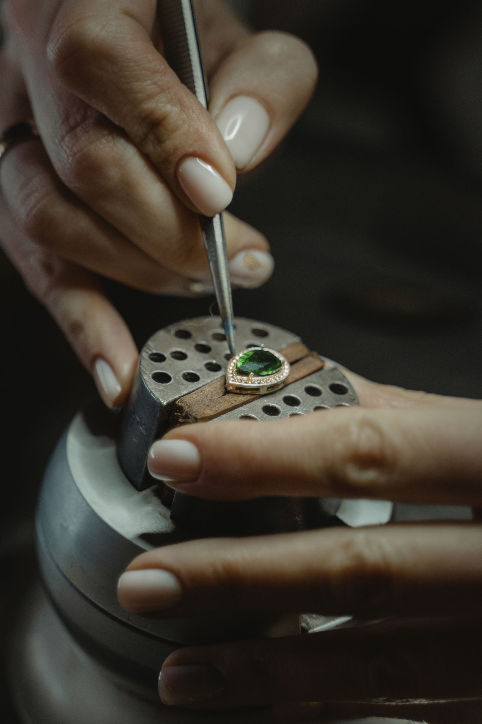 Jeweler setting a gemstone into a ring by hand at the workbench